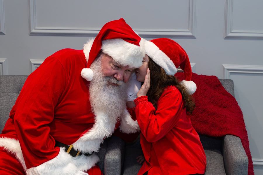 Santa listening to a child whisper her wish
