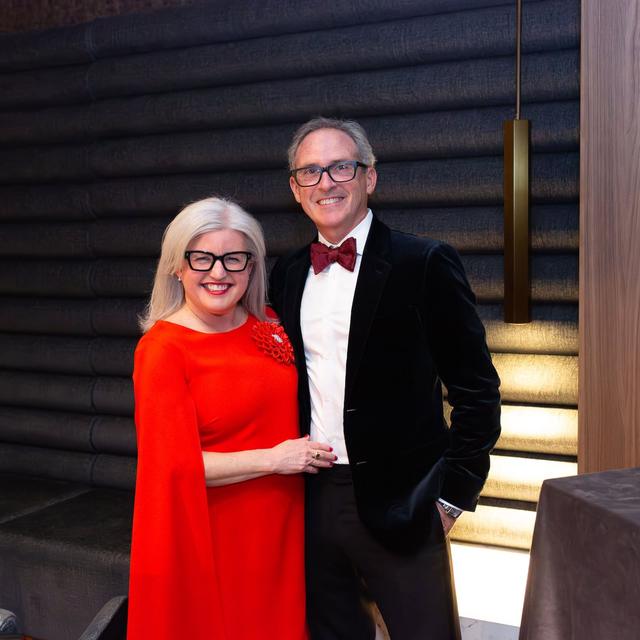 Couple in red and black posing at a holiday party
