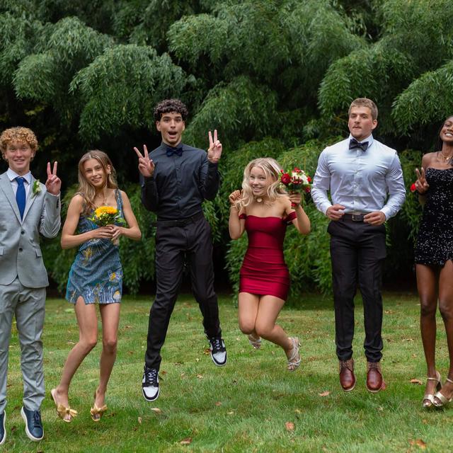 Teenagers jumping for a homecoming photo on the lawn
